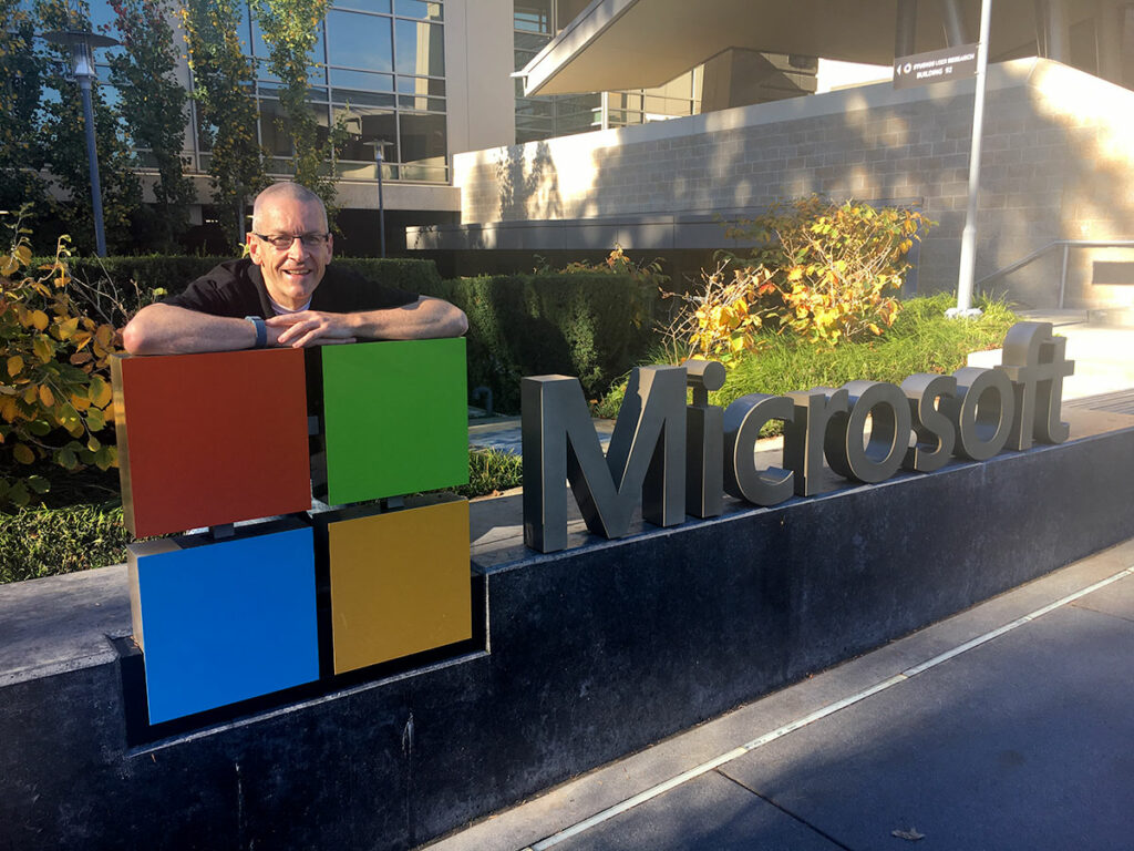 Greig leaning on the large Microsoft sign outside the main building at its headquarters in Redmond, Seattle